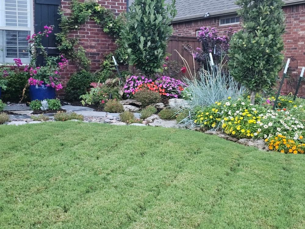 Vibrant flower garden with colorful blooms and lush green lawn in residential landscape.