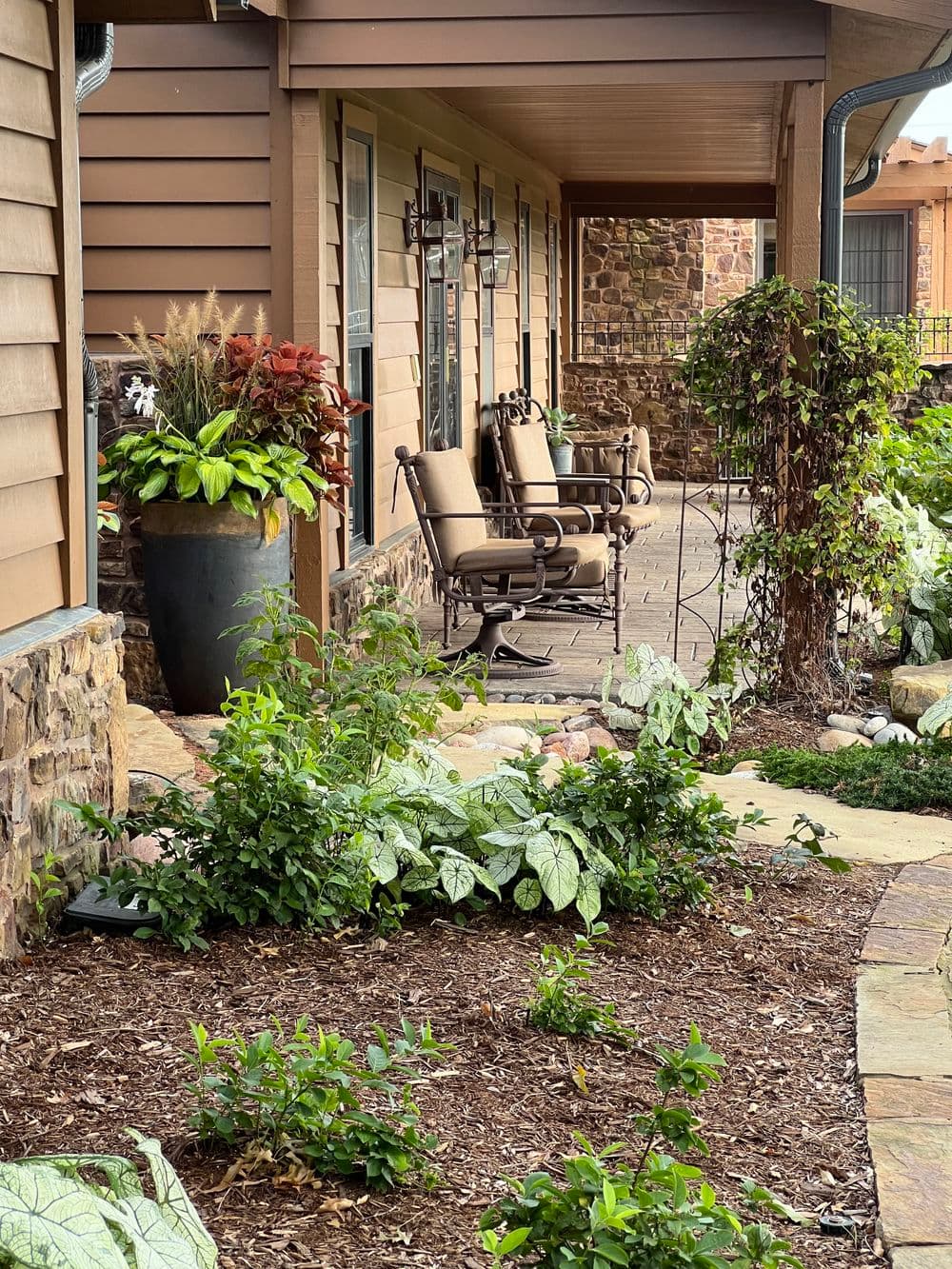 Cozy porch with rocking chairs and lush greenery in a charming outdoor garden setting.